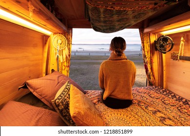 Woman Watching Sunset Over Beach From Bohemian Camper Van In A Van Life Theme