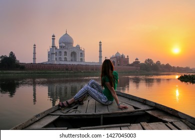 Woman watching sunset over Taj Mahal from a boat, Agra, India. It was build in 1632 by Emperor Shah Jahan as a memorial for his second wife Mumtaz Mahal.
