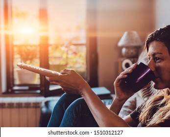 Woman Watching TV And Drinking Coffee / Tea On A Couch.