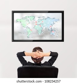 Woman Watching Tv. Photo From Behind. Worldmap At The Screen