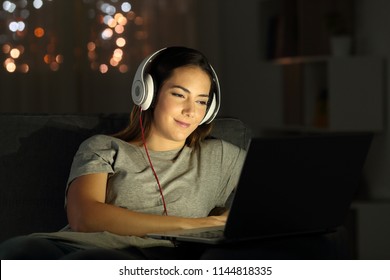Woman watching videos online in the night sitting on a couch in the living room at home - Shutterstock ID 1144818335