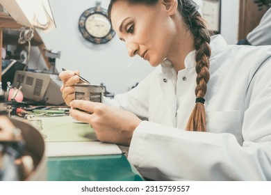 Woman watchmaker working diligently on repairing a watch - Powered by Shutterstock