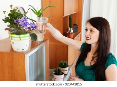 Woman Watering  Flowers In Pots At Home