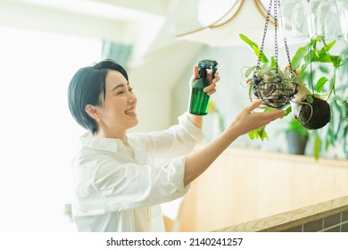 Woman watering houseplants before going to work - Powered by Shutterstock