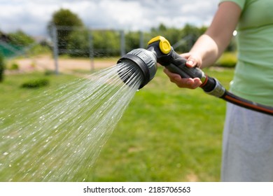 Woman Watering The Lawn With A Garden Hose With A Watering Can