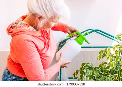 Woman Is Watering Plants With Pressure Water Pump Sprayer. Home Gardening Concept.