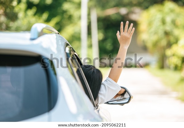 A woman\
waved from a car window to drive\
forward.
