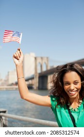 Woman Waving American Flag At Urban Waterfront