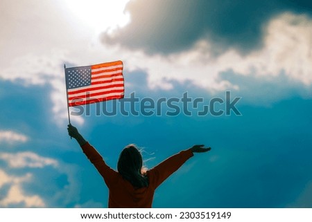 
Woman Waving the Flag of the United Stated of America. American citizen celebrating 4th of July 
