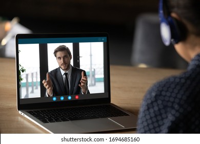 Woman wear headphones listen tutor during online class pc screen view over trainee shoulder. Colleague express opinion share ideas working together on project using video call, e-learn e-coach concept