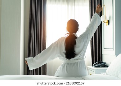 woman wear nightgown raising arms waking up happy concept in early good morning sitting in cozy bed