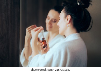 
Woman Wearing a Bathrobe Using an Anti-Aging Serum. Lady in her 30s doing her skin care routing every night

