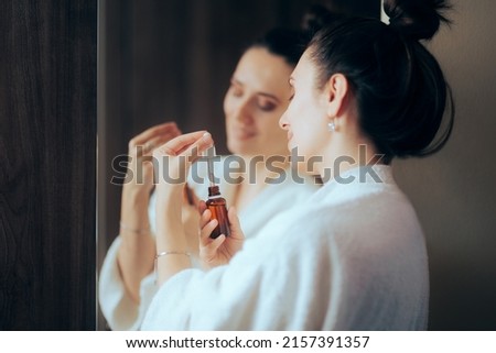 
Woman Wearing a Bathrobe Using an Anti-Aging Serum. Lady in her 30s doing her skin care routing every night
