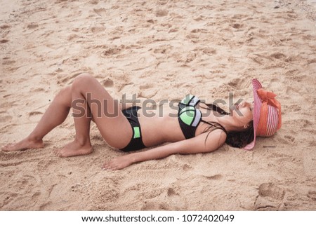 Woman wearing beach hat is sleeping on the sand.