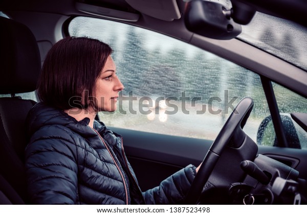 Woman wearing black jacket driving car on the\
motorway in the rain