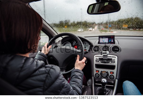 Woman\
wearing black jacket driving car on rainy\
day