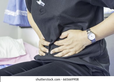 Woman wearing a black shirt sitting on the bed,severe abdominal pain patients in the emergency room of the hospital.