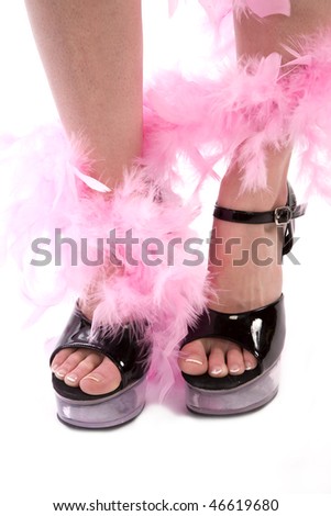 A woman wearing black shoes with a pink feather boa wrapped around her legs.