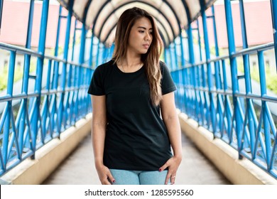 Woman wearing black t-shirt posing in outdoor. 