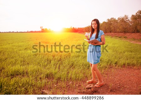 Woman wearing a blue dress holding a cup coffee .At the sunset.