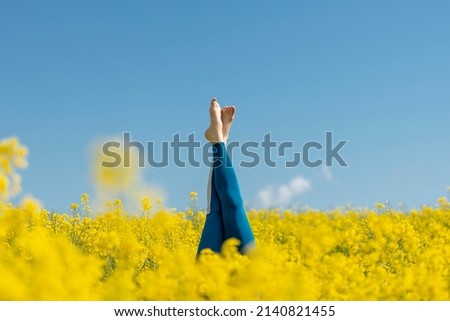 woman wearing blue leggings doing a headstand in a yellow field