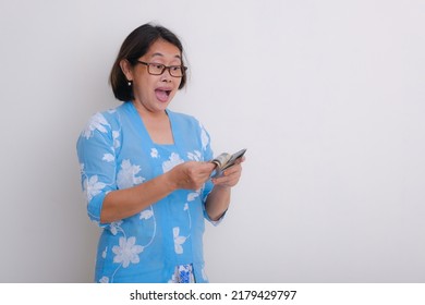 A Woman Wearing A Blue With White Floral Print Dress Counting Some Money; Happy, Surprised Expression.