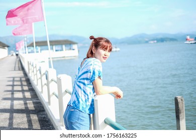 A Woman Wearing A Blue And White Tie Dye Shirt , Tied Two Hair Sticks To Watch The Sea