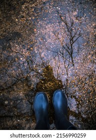 A Woman Wearing Boots With Her Reflection On A Puddle Of Water After A Rain