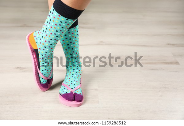 Woman wearing bright socks with flip-flops\
standing on floor. Space for\
design