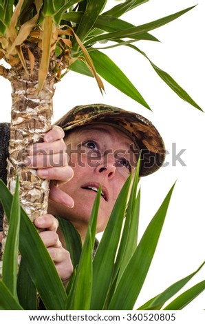 Woman wearing camouflage looking up a tree against white background