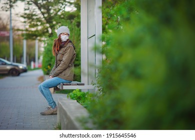 A Woman Wearing A Cloth Face Mask Waits At A Public Transport Stop. The Woman Is Protecting Herself From Corona Virus And Other Airborne Particles And Diseases. 