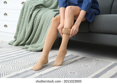 Woman wearing compression tights in living room, closeup