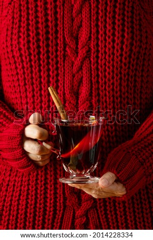 Woman wearing cozy red pullover holding a cup of mulled wine, front view winter holidays traditional recipes concept