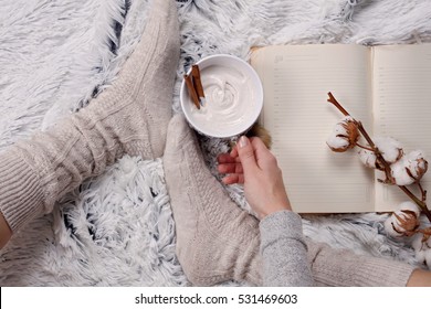 Woman Wearing Cozy Warm Wool Socks, Reading A Book, Drinking Hot Drink Lose Up. Warmth Concept. Winter Clothes