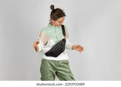 Woman Wearing Crossbody a Black Leather Belt Bag over Grey Background. Handmade Leather Accessories Goods