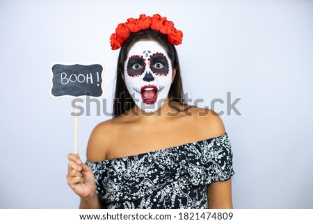 Woman wearing day of the dead costume over isolated white background surprised with booh word message