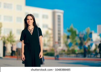 Woman Wearing Elegant Romper And Statement Necklace At Outdoor Event. All Black Dress Code Outdoor Party Guest Arriving To Dinner
