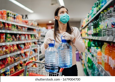 Woman wearing face mask buying bottled water in supermarket/drugstore with sold-out supplies.Prepper buying bulk supplies due to Covid-19 or Coronavirus and panic buying concept.