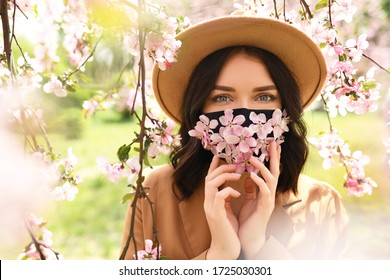 Woman wearing face mask decorated with flowers. Stylish handmade cotton mask. Spring blossom garden - Powered by Shutterstock