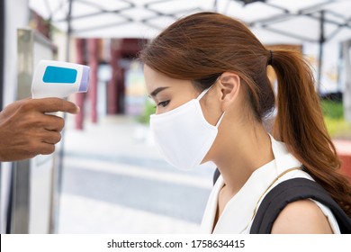 woman wearing face mask getting infrared thermal scanned for fever at check point - Powered by Shutterstock