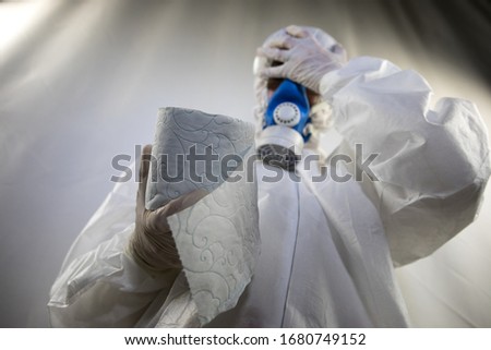 A woman is wearing a face mask for protection from the Corona Virus and has stocked up on her toilet paper stash in case of quarantine. Selective focus