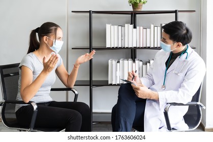 Woman Wearing Face Mask Sitting On The Armchair And Talking To The Professional Psychologist While Wearing Face Mask Conducting A Consultation And Making Notes During Coronavirus Or COVID 19 Outbreak