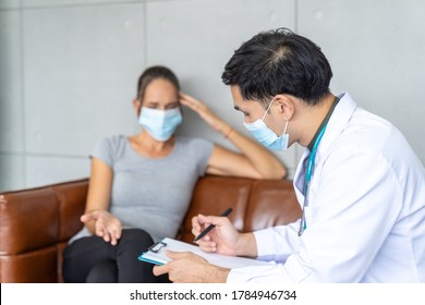 Woman Wearing Face Mask Sitting On The Sofa And Talking To The Professional Psychologist While Wearing Face Mask Conducting A Consultation And Making Notes During Coronavirus Or COVID 19 Outbreak