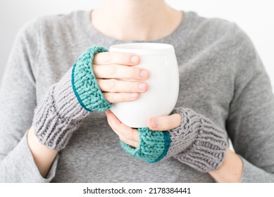 A Woman Wearing Fingerless Mittens Holds A Coffee Mug