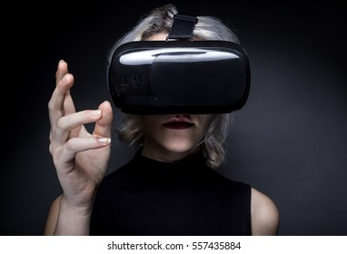 Woman Wearing A Futuristic Looking Virtual Reality Headset Goggles.  The Device Is Technology That Lets Video Gamers Experience VR Or AR Augmented Reality