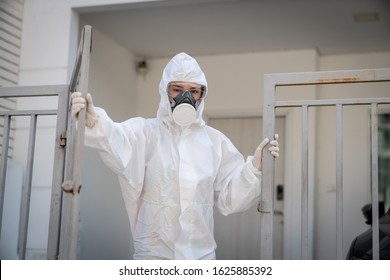 Woman wearing gloves with biohazard chemical protective suit and mask.with unhappy face. Opening an iron gate.