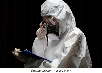 Woman wearing gloves with biohazard chemical protective suit and mask. is writing report on paper.