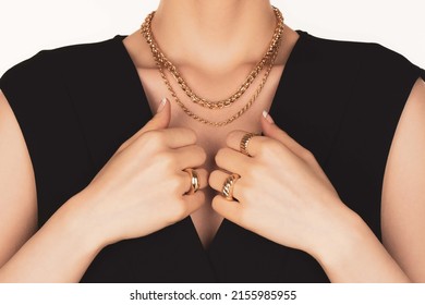 Woman Wearing Gold Jewellery And A Black Dress. Two Gold Chain Necklaces And Three Golden Rings. 