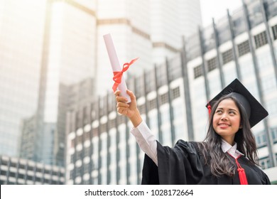 Woman Wearing Gown Raising Hand With Success Bachelor Degree Of University