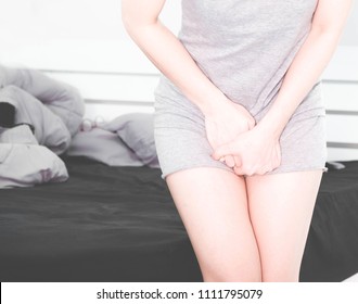 Woman Wearing Gray Clothes Stand By The Bed, Bottom Pain And Rod,Acute Inflammation In A Woman Dermatitis . Female Holding Hand To Spot Of Itchy